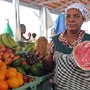 Vendeira mostra frutas no seu posto de venda